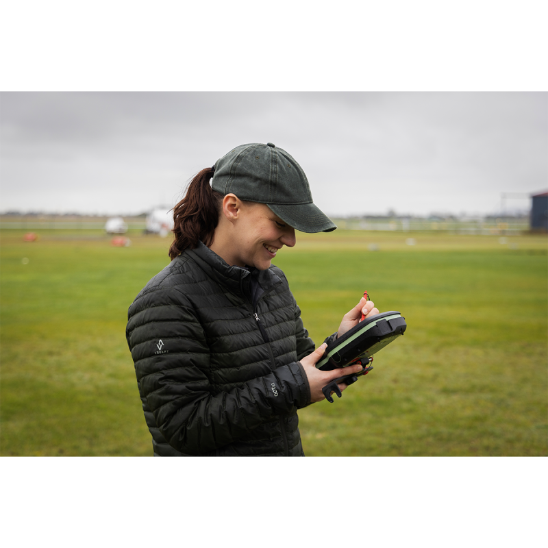 A researcher smiling while looking down at an electronic measuring device.