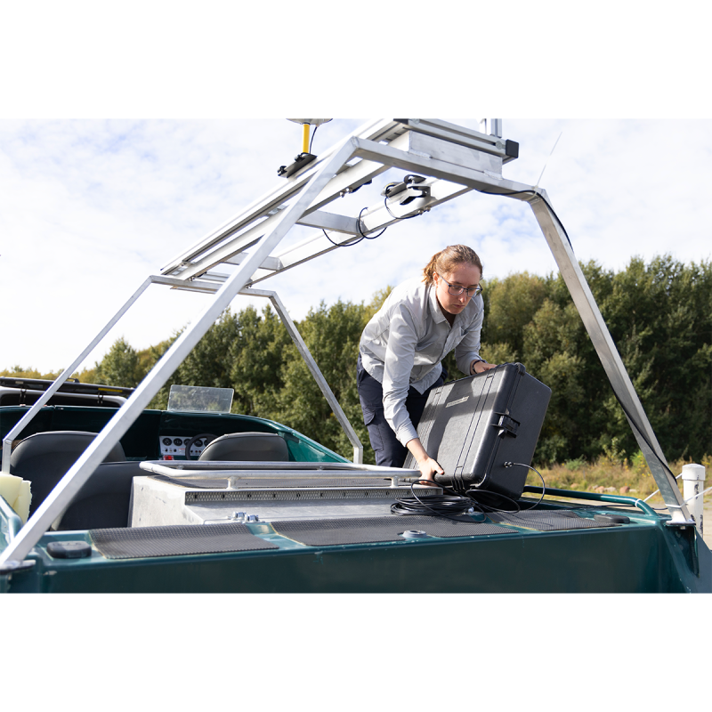 A researcher configuring a GPS in a boat on the water.