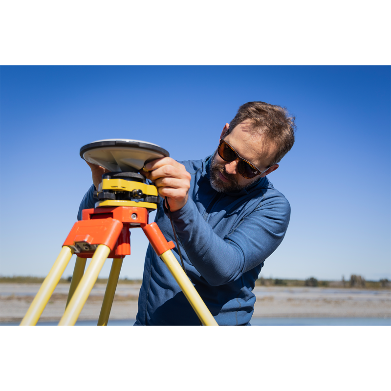 A researcher configuring a measurement tool near a river.