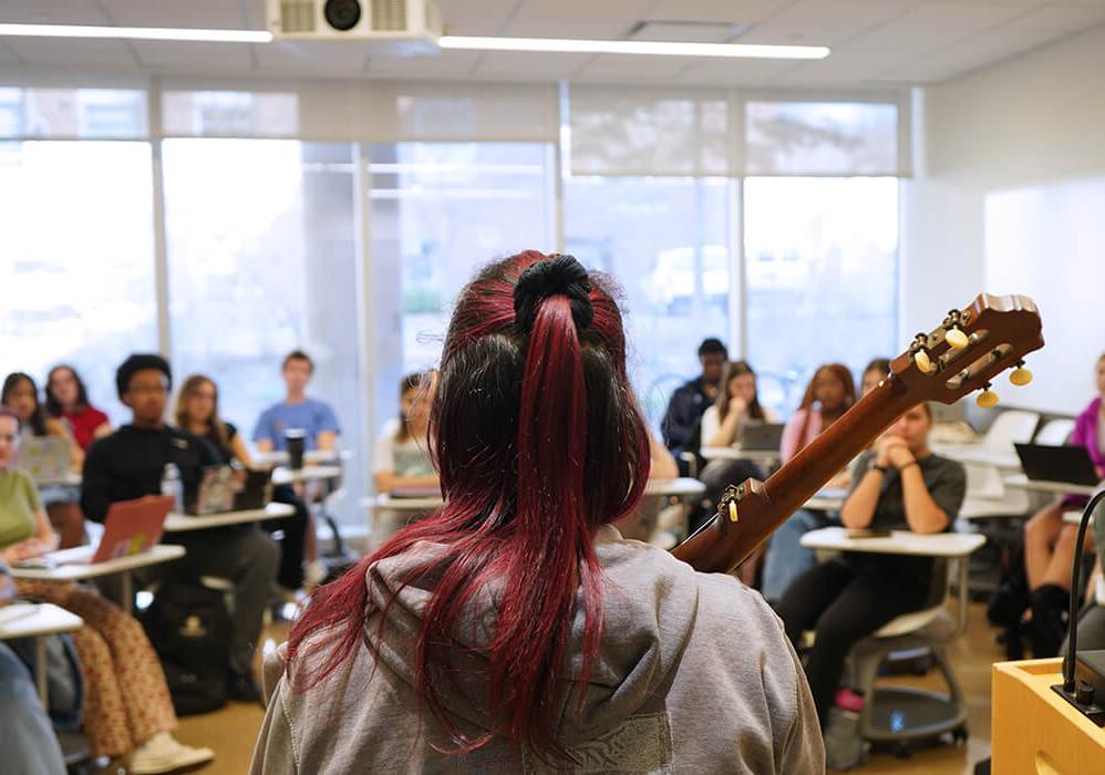 Back of Rhiannon Giddens' head amongst a classroom of students.