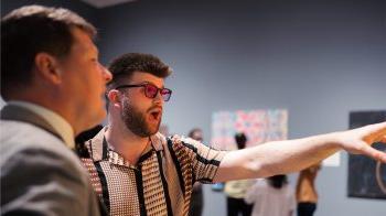 Logan Moore, donning a pair of Enchroma glasses, looks in amazement at art in the Ackland.