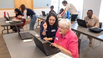 A UNC-Chapel Hill student instructor, Rebecca Topper, giving one-on-one help to a library patron, Jan Touma, during a workshop on digital literacy.